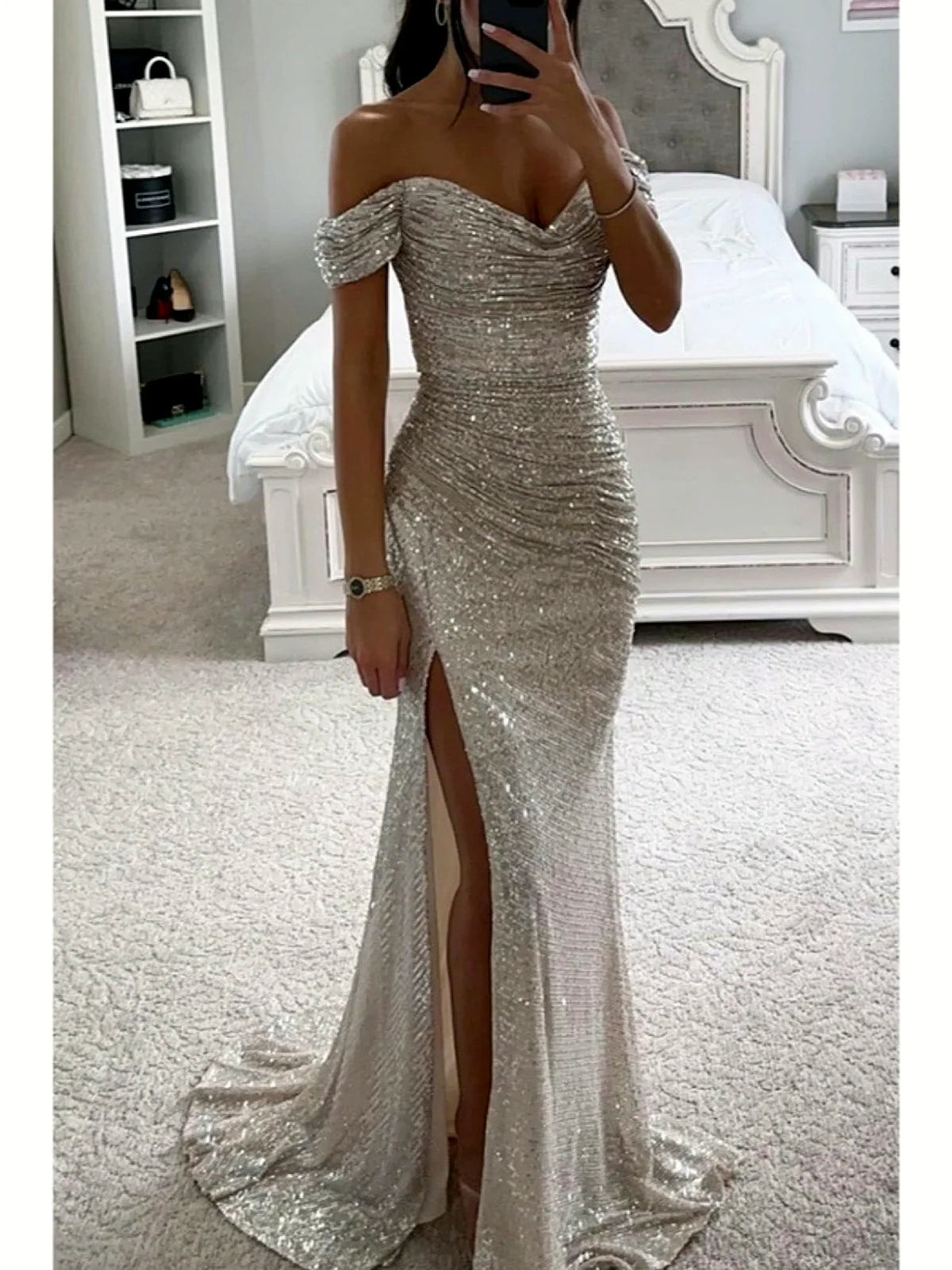 Women's sequin off-shoulder slit evening gown in silver, front mirror view.