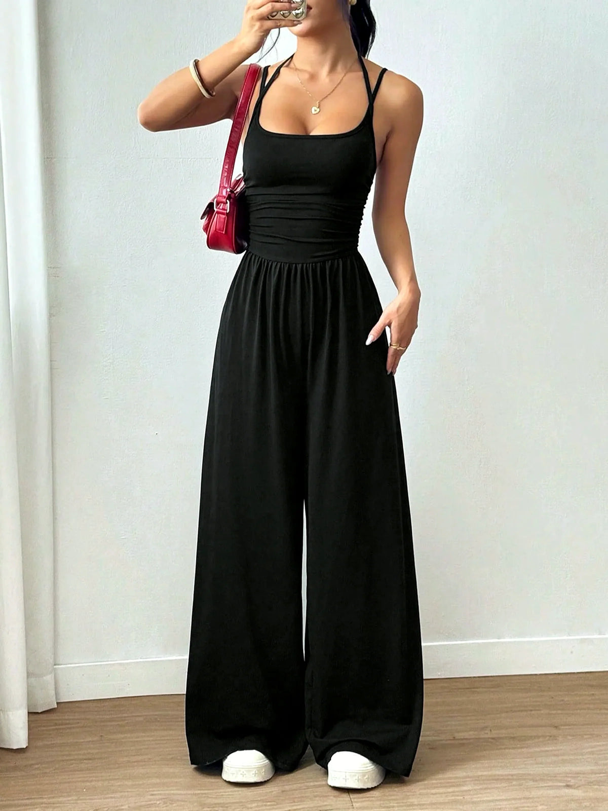 Women's sleeveless ruched-bodice wide-leg jumpsuit in black, front model view.