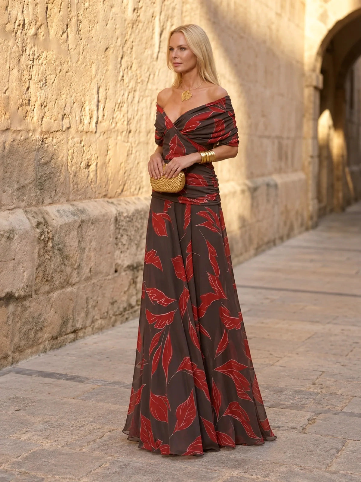 Women's ruched off-shoulder flowing dress in black and red leaf print, front model view.