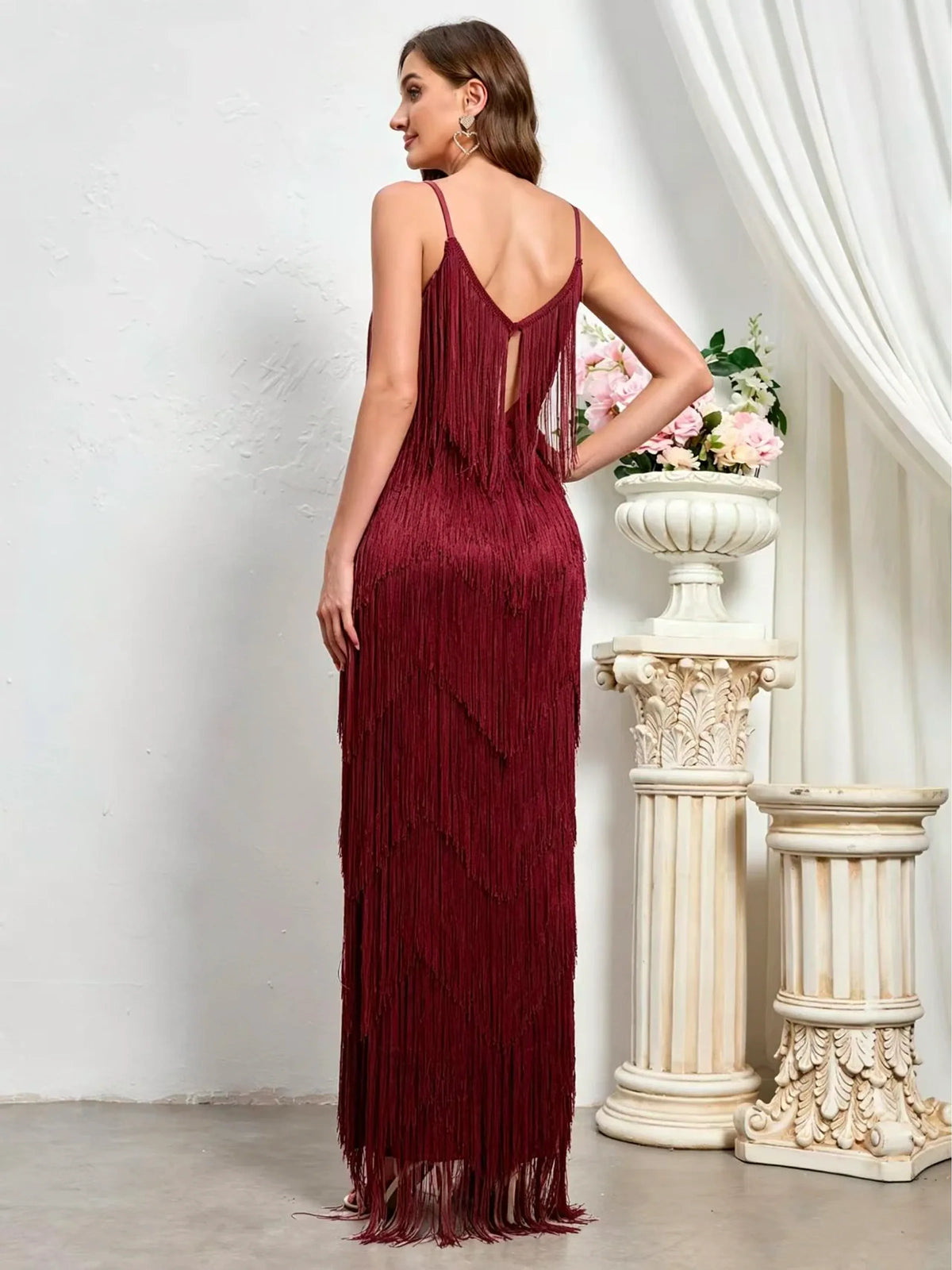 Women's sleeveless tiered fringe maxi dress in burgundy, back model view.