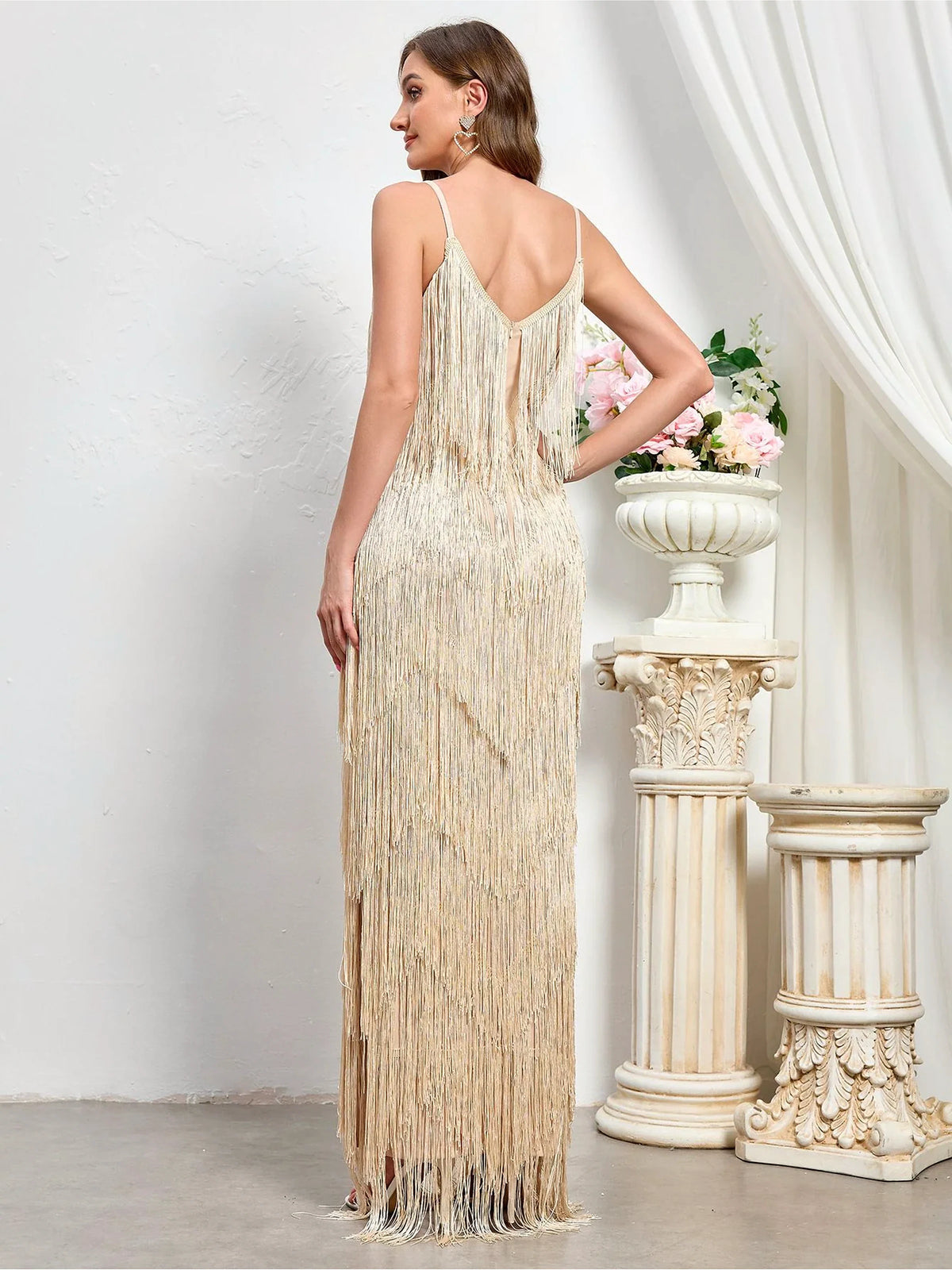 Women's sleeveless tiered fringe maxi dress in ivory, back model view.