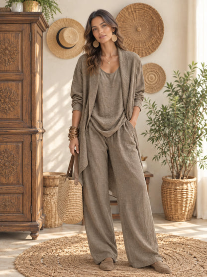 Women’s textured relaxed-fit top and wide-leg pants set in taupe, styled with an open-front layer in a warm interior.