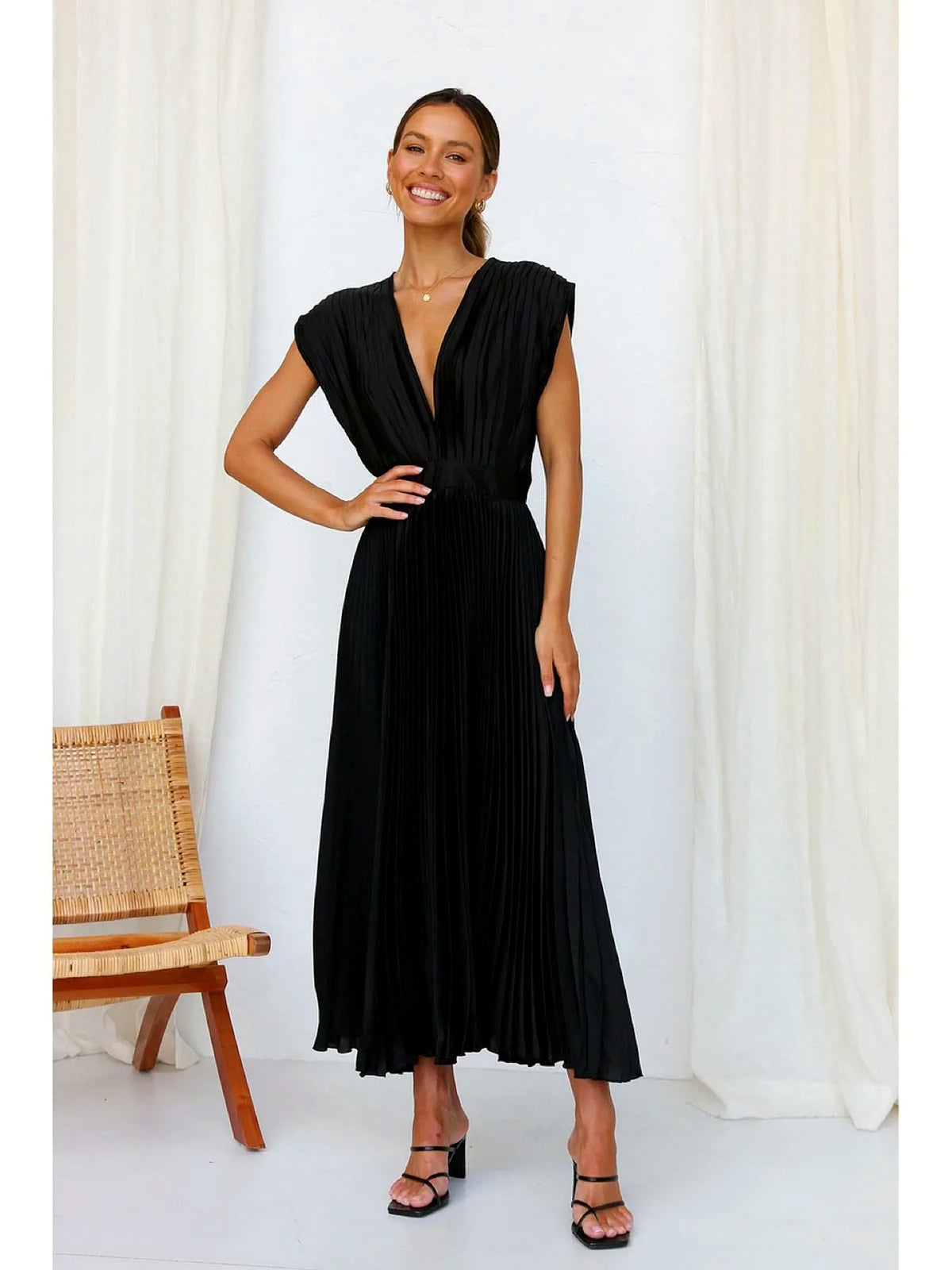 Women's V-neck pleated midi dress in black, front model view.